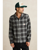 Man wearing a plaid shirt and cap with a visible brand logo on a beige background Rhythm Alex Check LS Shirt - Forest