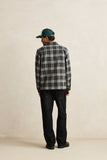 Person wearing a plaid shirt and dark pants with a cap, standing against a plain background Rhythm Alex Check LS Shirt - Forest