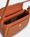 Brown leather handbag with floral embossing on a light gray background