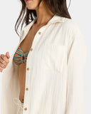 Woman wearing a white button-up shirt over a patterned top on a plain background Billabong Wanderer LS Woven Top - Salt Crystal