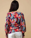 Woman wearing a colorful floral blouse against a beige background Charlo Tamara V Neck Top - Floral
