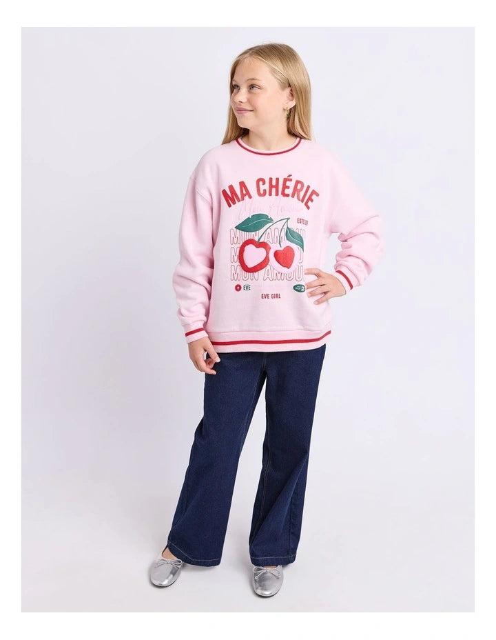 Young girl wearing a pink sweatshirt with text and graphics, standing against a white background Eve Girl Cherry Hearts Crew - Pale Pink