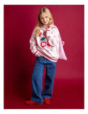 Young girl wearing a pink sweatshirt with red accents and blue jeans on a red background Eve Girl Cherry Hearts Crew - Pale Pink