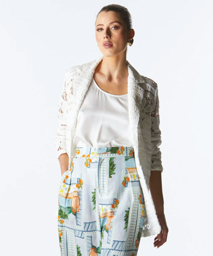A woman wearing an ivory lace blazer over a white top and tropical print pants. Fate + Becker Worth It Lace Blazer - Ivory