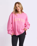 Woman wearing a pink sweatshirt with 'FOXWOOD' printed on it against a white background
