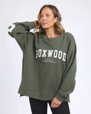 Woman wearing a green sweatshirt with 'FOXWOOD' printed on it against a white background