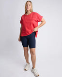 Woman wearing a red oversized t-shirt and navy shorts on a white background