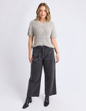 Woman wearing a patterned short-sleeve shirt and dark pants on a white background Foxwood Davana Knit - Oat Marle