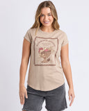 Woman wearing a beige t-shirt with a graphic design on a plain background