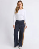 Woman wearing a white sweater and navy pants with a gold stripe on a white background Foxwood Juno Pant - Ink