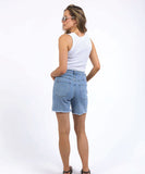 Woman wearing light blue denim shorts and a white sleeveless top on a white background