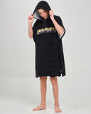 A child wearing a black hooded towel poncho with a yellow and blue 'The Mad Hueys' graphic across the chest, standing barefoot against a light gray studio background.