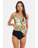 A woman modeling a one-piece swimsuit with a tropical floral and patchwork print top and solid black bottoms, photographed against a light gray studio background.
