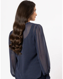 Woman wearing a blue mesh top with long dark hair on a white background