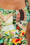 Close-up of a person wearing a colorful patchwork-print halter top with tropical floral and paisley fabric panels.