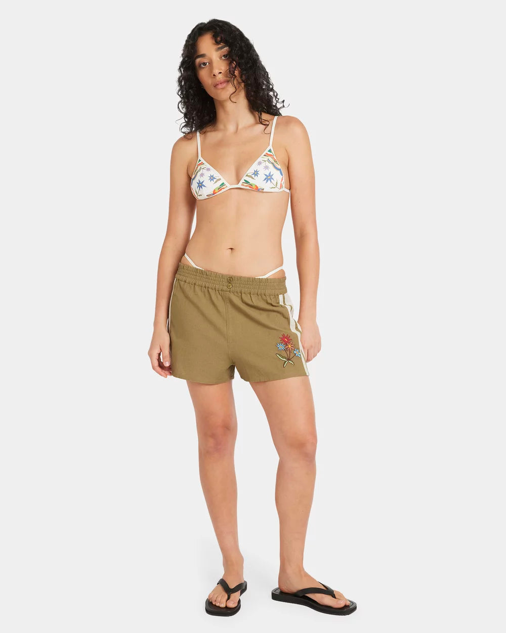Woman wearing a floral bikini top and green shorts on a white background RVCA Womens Mel G Elastic Waist Shorts - Olive