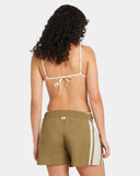 Woman wearing a white bikini top and green shorts with a white stripe on a light gray background RVCA Womens Mel G Elastic Waist Shorts - Olive