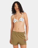 Woman wearing a floral bikini top and green shorts with floral embroidery on a white background