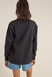 Person wearing a black sweatshirt and denim shorts on a beige background