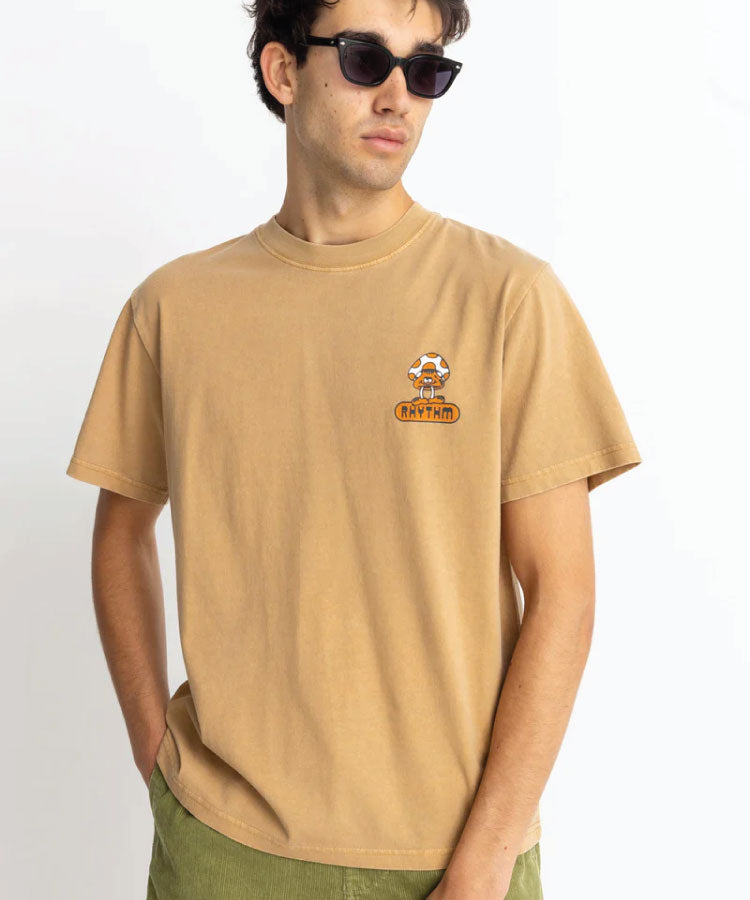 A person wearing a beige short-sleeved T-shirt with a small graphic logo on the chest.