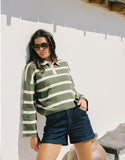 Woman wearing a green and white striped sweater and blue shorts indoors. Rhythm Rugby Polo Knit Sweater - Olive