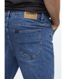 Close-up of blue jeans with a visible brand label on a white background Riders R3 Narrow Magnitude Jeans