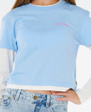 Light blue sweatshirt with pink text worn by a person, paired with light blue jeans. Rip Curl Aggie Relaxed Kids Jeans - Vintage Blue