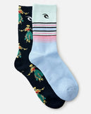 Two crew socks from Surf Life Island shown on a light gray background. One sock is dark navy with a colorful surfer pattern, and the other is light blue with pink and black stripes and a black logo.