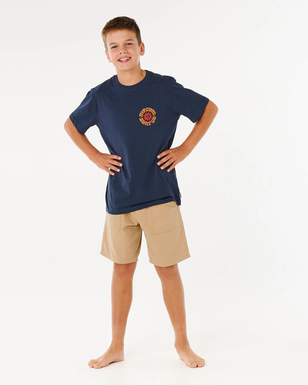 Child wearing a navy blue t-shirt with a logo and beige shorts on a white background