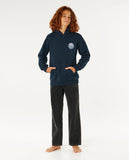 Person wearing a navy hoodie with a logo and dark pants on a white background Rip Curl Wetsuit Icon Kids Hood - Navy/White