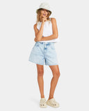 Person wearing a white sleeveless top, light blue denim shorts, and cream Crocs on a white background