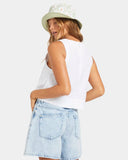Woman wearing a white sleeveless top and light blue denim shorts on a white background