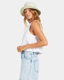 Woman wearing a white sleeveless top and light blue jeans with a white background