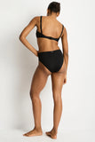 A woman modeling a black two-piece swimsuit from the back, showing the back straps of the bikini top and the high-cut bikini bottom, against a plain white studio background.