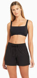 Woman wearing a black sports bra and shorts set on a white background