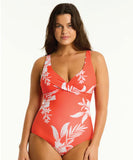 A woman wearing a red one-piece swimsuit with a floral pattern, featuring a cross front design.