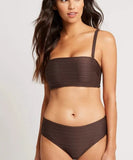 A woman modeling a dark brown ribbed two-piece bikini set against a plain light gray studio background.