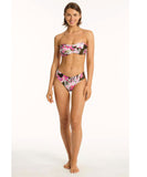 A female model wearing a floral mid-rise bikini bottom with a matching strapless top.