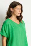 Woman wearing the Sea Level Sunset Kaftan - Kelly Green shirt against a plain background