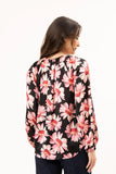 Woman wearing a black long-sleeve top with pink floral pattern on a white background Back view