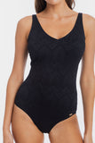 A woman wearing a black one-piece swimsuit with a textured chevron pattern, shown from the neck down against a plain white background.