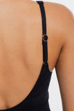 Close-up back view of a person wearing a black spaghetti-strap top with a gold-tone adjustment buckle.