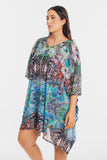A woman modeling a short, flowy kaftan-style dress with a vibrant multicolor tropical and zebra print, set against a plain light gray background.