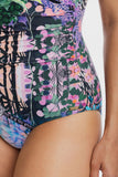 Close-up of a model wearing a high-waisted one-piece swimsuit with a vibrant multicolor tropical floral and leaf print on a white background.