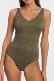 A woman wearing a sleeveless one-piece swimsuit with a textured geometric chevron pattern in olive green, shown against a plain light gray background.