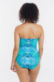 Rear view of a woman with curly dark hair wearing a strapless one-piece swimsuit with a blue and turquoise tie-dye pattern, set against a plain white background.