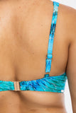 Close-up back view of a person wearing a bikini top with blue and turquoise abstract print straps and a gold-tone clasp.