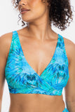 A close-up of a woman wearing a vibrant blue and turquoise tie-dye bikini top with a deep V-neck and crossover front, set against a plain white background.