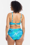 A woman shown from the back wearing a two-piece bikini with a blue and turquoise tropical leaf pattern, set against a plain white studio background.