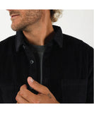 Close-up of a person wearing a black corduroy shirt with a plain background T&C Motion LS Cord Shirt - Midnight